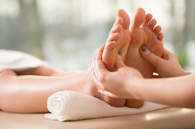 Person receiving a relaxing foot massage during a reflexology session, with pressure being applied to specific points on the foot.